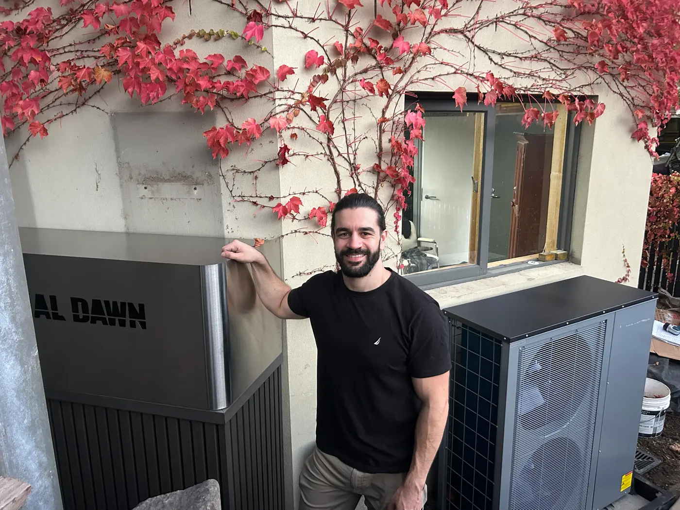 A Thermal Dawn engineer beside the installed thermal store and heat pump at a Hawthorn home
